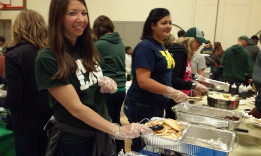 More teachers smile to the camera as they serve up some pancakes.