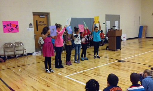 Students hold up colorful signs.