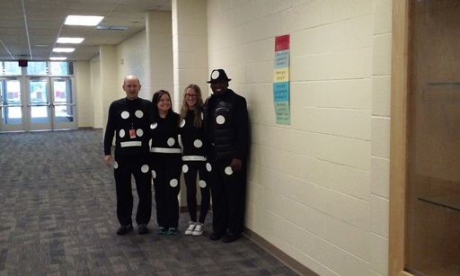 Three teachers and the principal grin as their photo is taken.