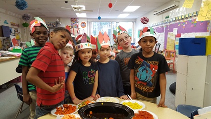 The kids show off their hats made from colorful paper.